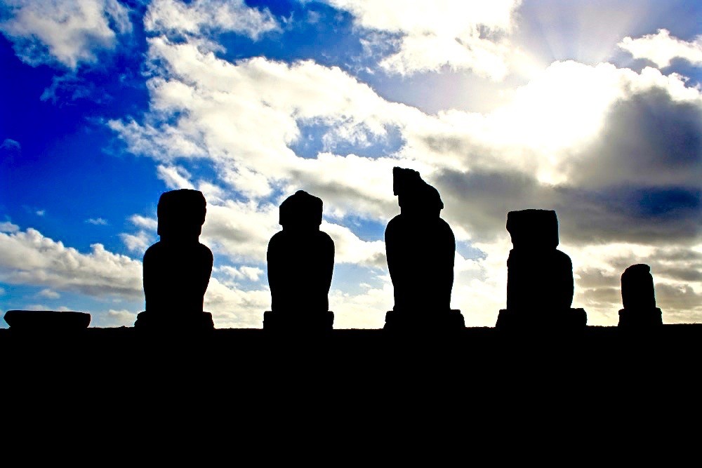 A line of moai silhouetted against the sun