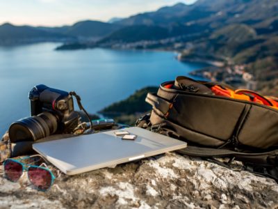 a laptop, camera and bag for how to start a travel blog