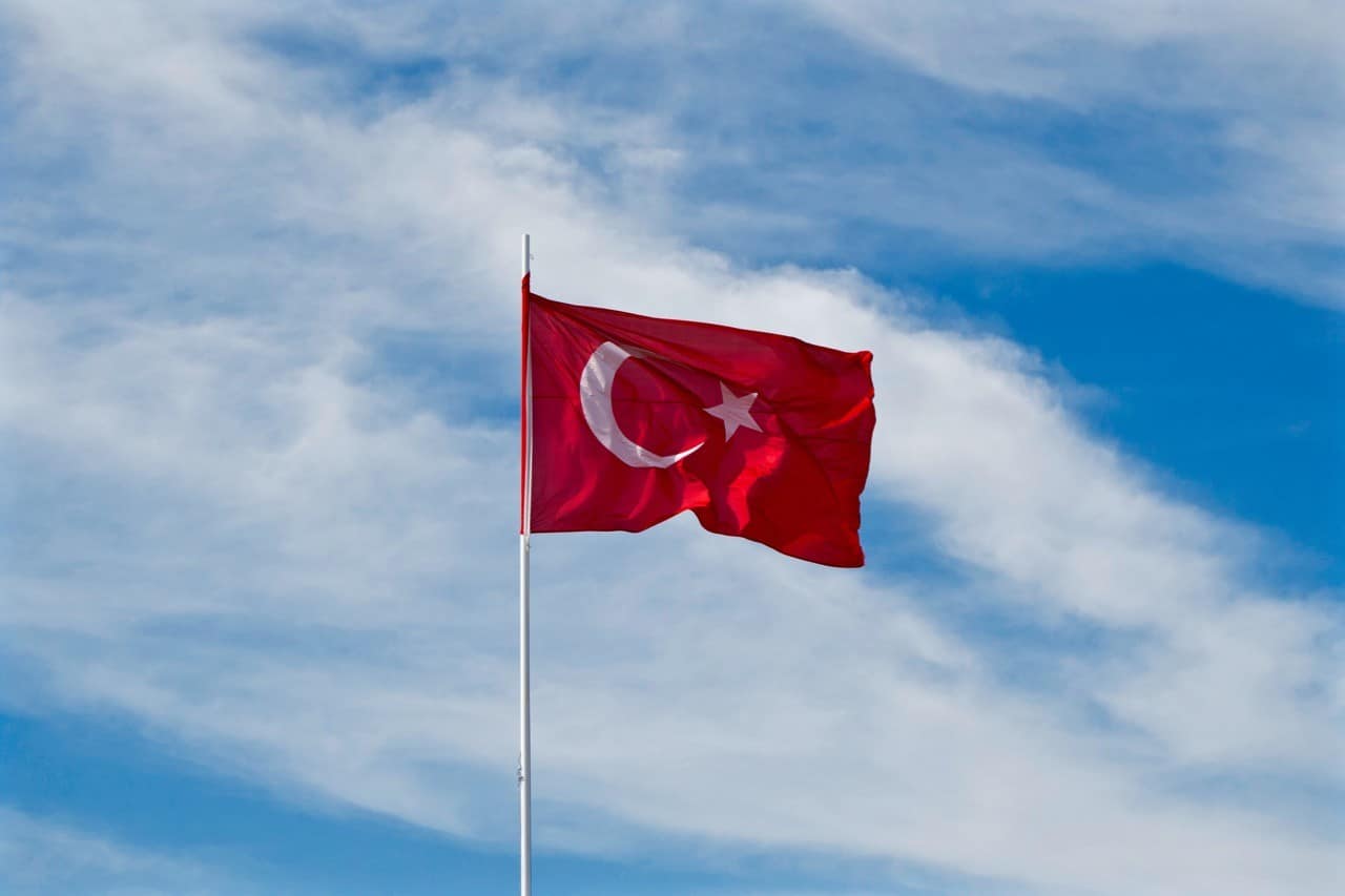 A Turkish flag flies against blue skies