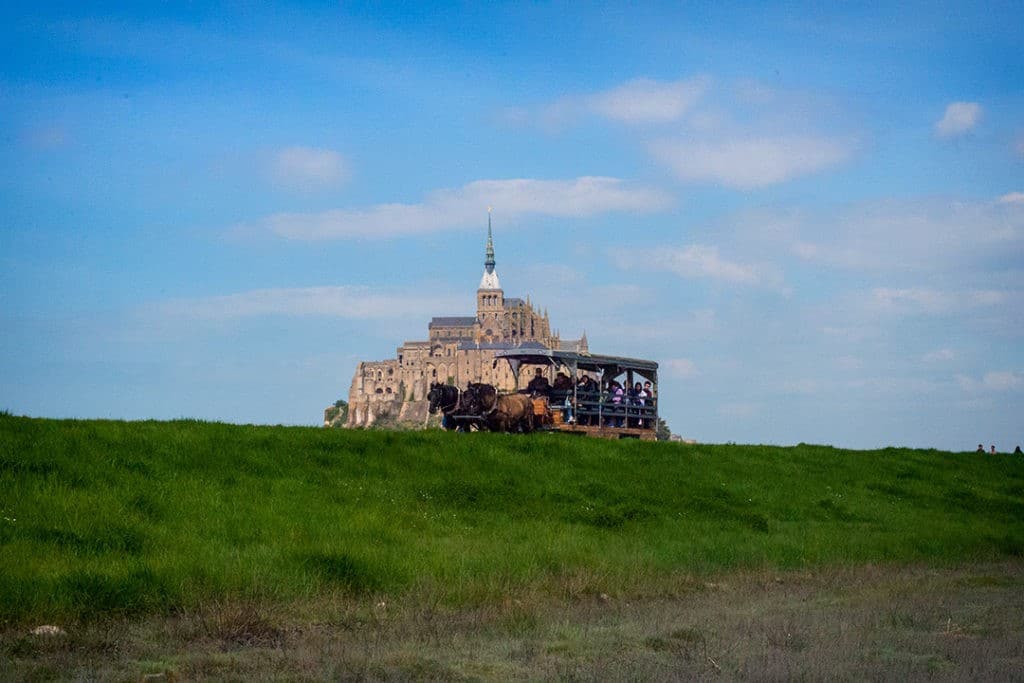 A horse-drawn carriage passes Mont Saint-Michel