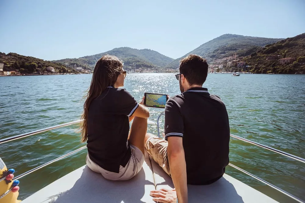 a couple using a sailing app on a device while sailing