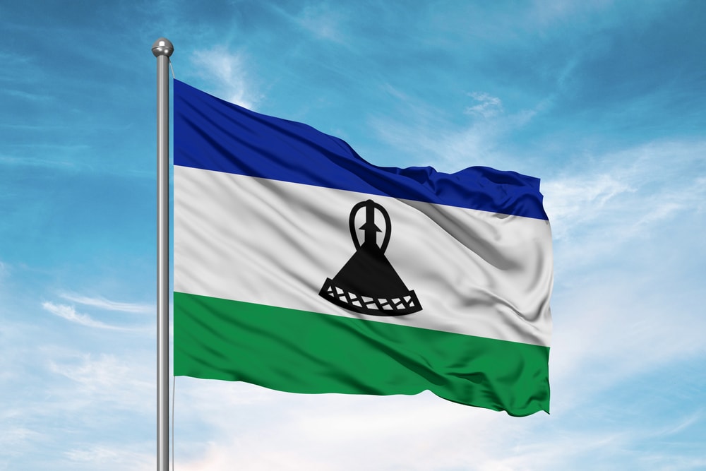 Lesotho's flag flying against a blue wispy sky