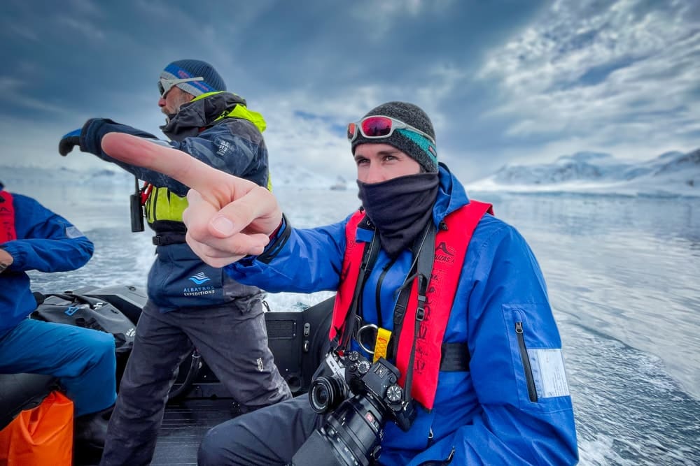 Peter on a zodiac boat with his travel photography gear around his neck