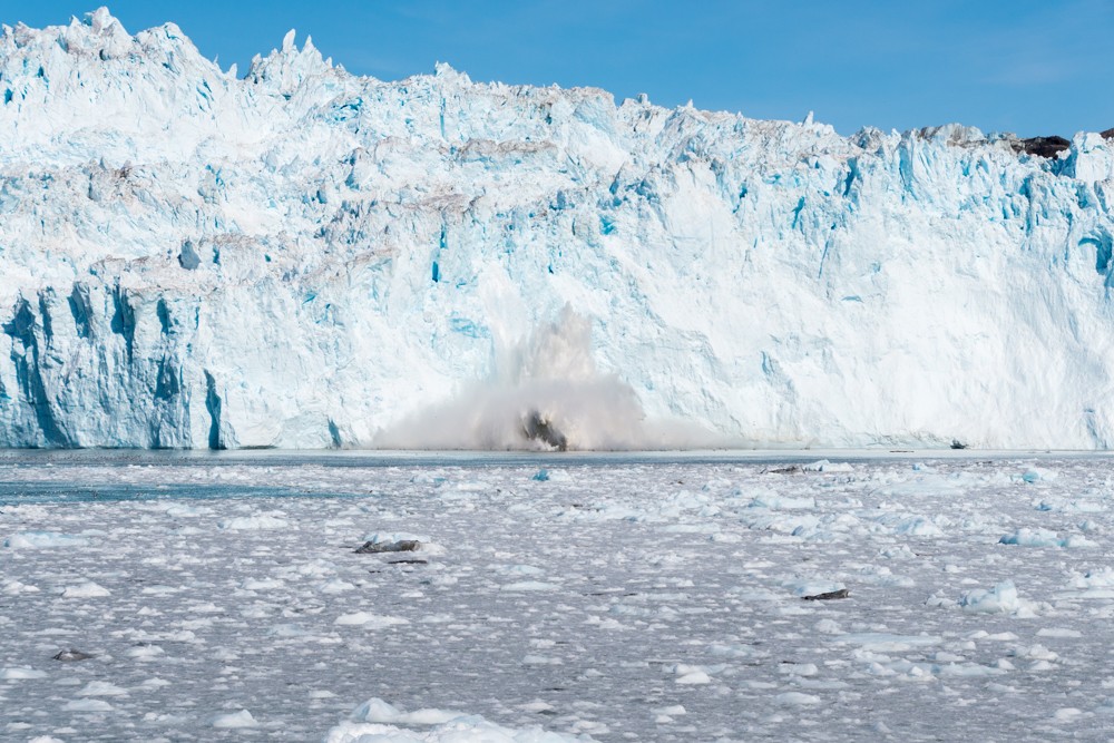 A chunk of ice carves off Eqi Glacier