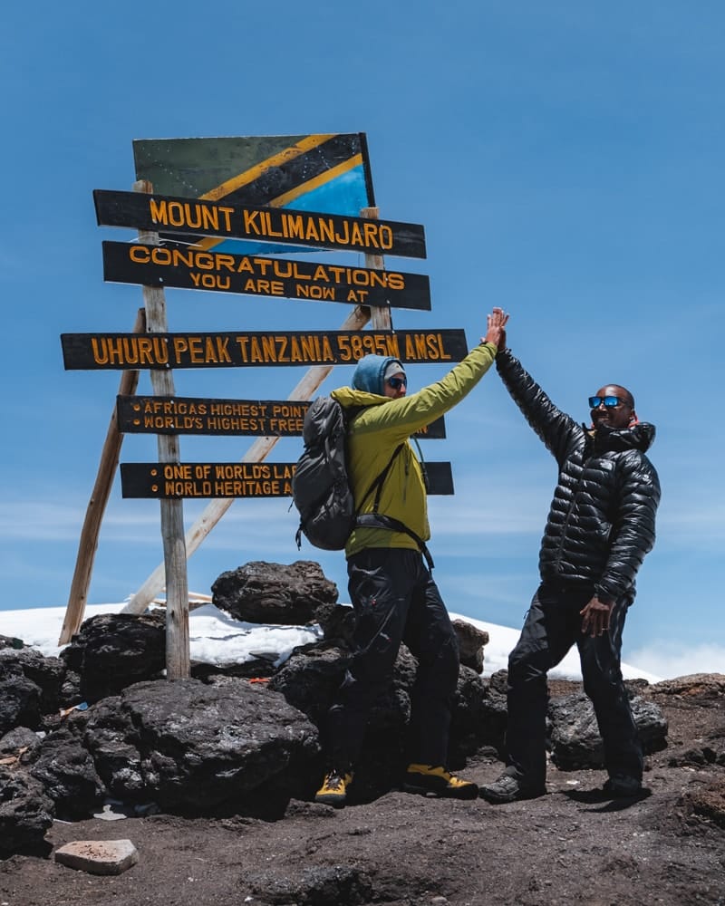 A trekker celebrates with a guide at the summit