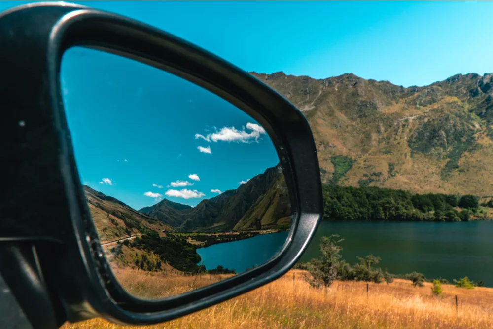 car wing mirror with reflection of mountains – selling our car as part of our climate pledge