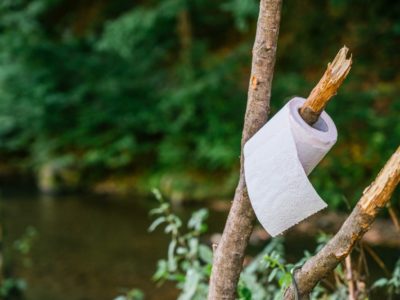 A toilet roll hanging on a branch in the wild