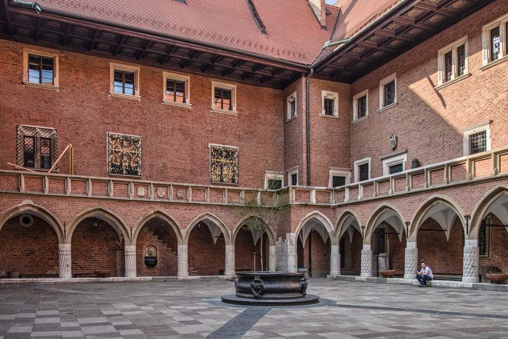 A man sits in the arched courtyard in the Kraków Old Town