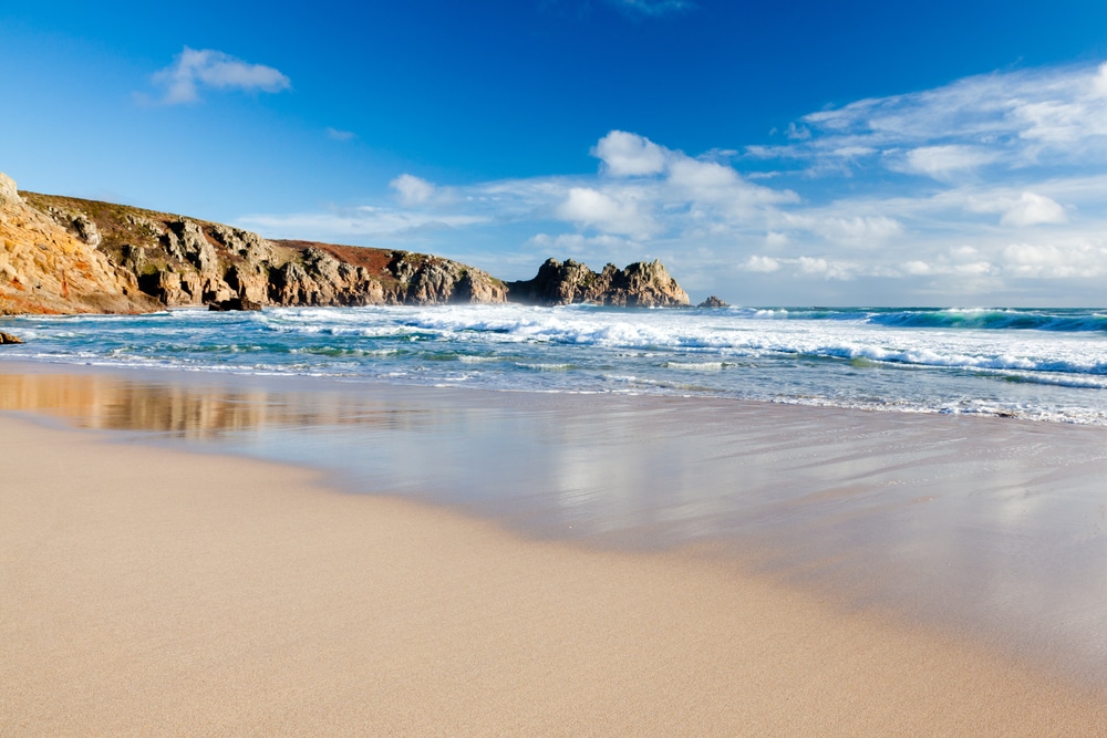 Porthcurno beach with waves crashing in the background - where to stay in cornwall