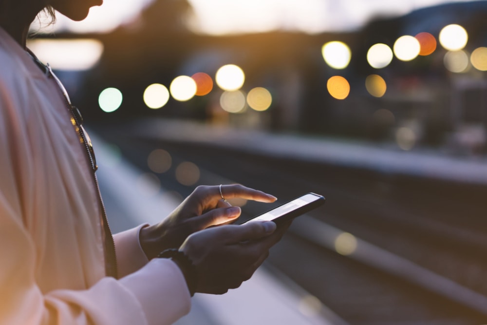 A traveller using a phone on a train platform with an eSIM for travel in Europe