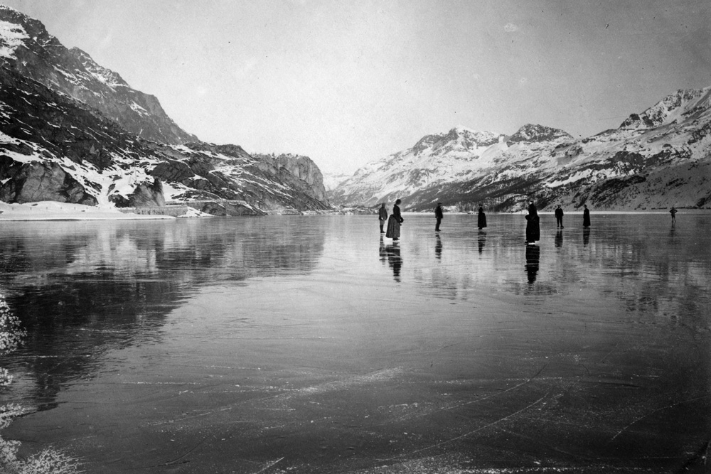 A black and white photo of an iced lake with skaters