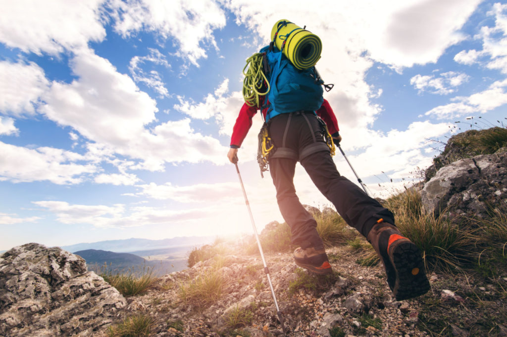 A trekker using poles uphill on a mountain