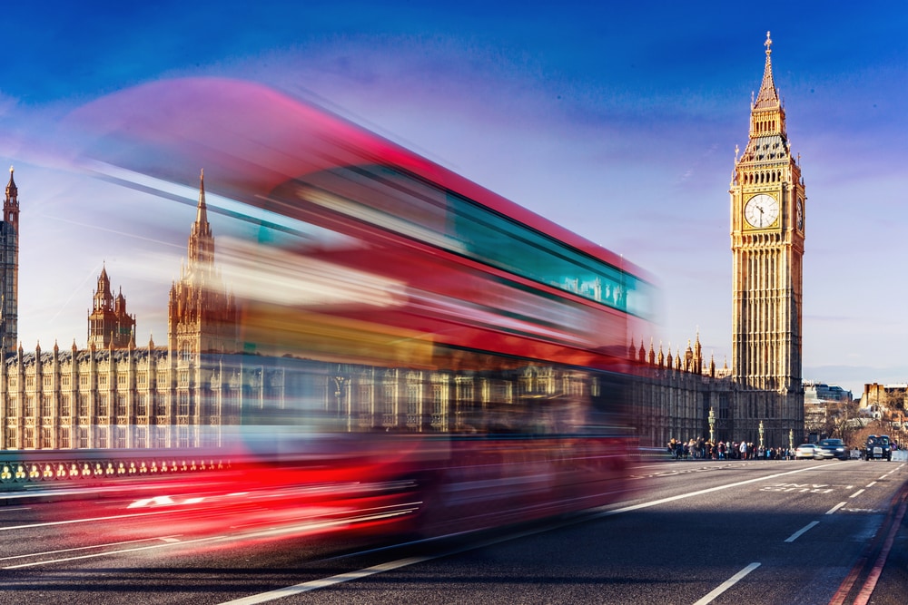 A city of London bus crosses a bridge in fron of Big Ben