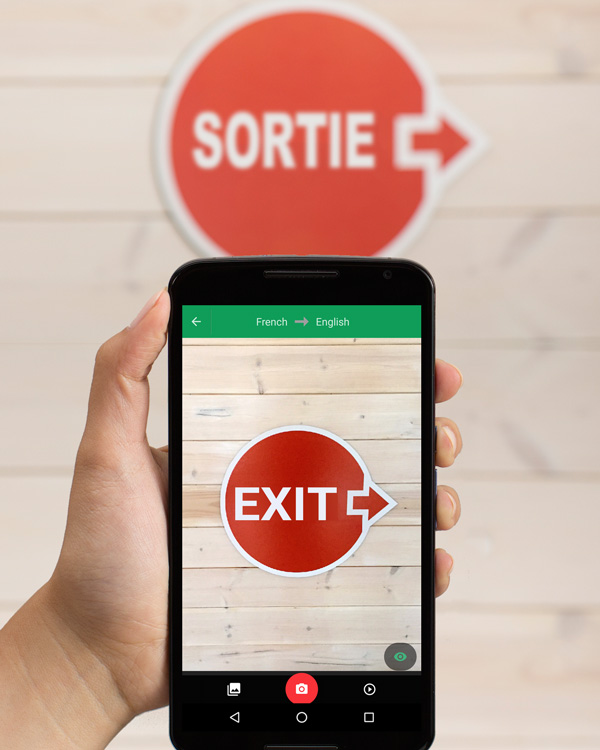 A person using their smartphone to translate an exit sign from French