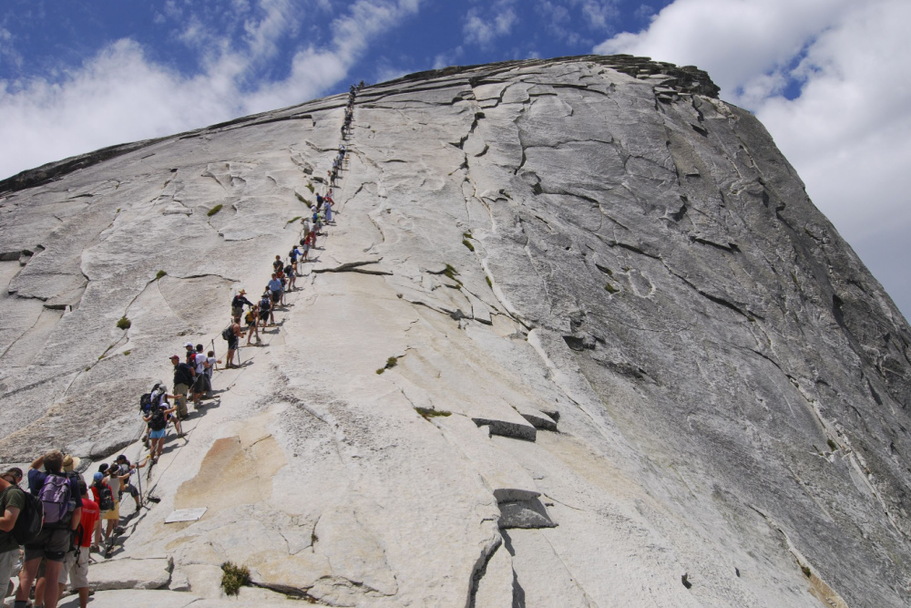 A line of hikers approach the summit of Half Dome