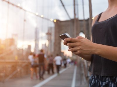Young woman using smart phone on Brooklyn Bridge