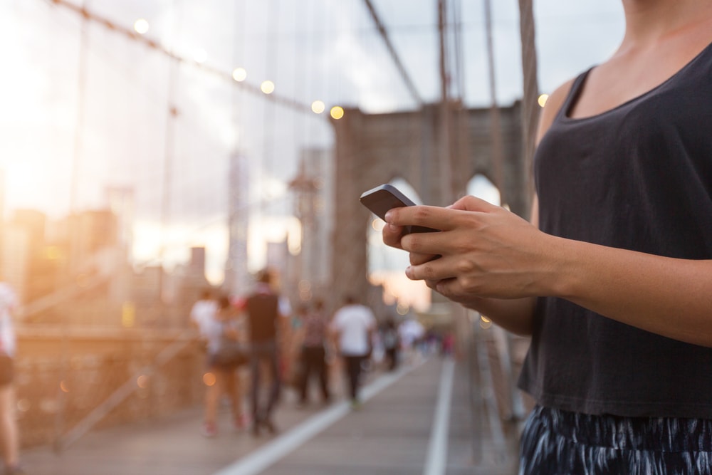 Young woman using smart phone on Brooklyn Bridge