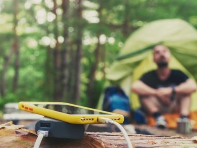 phone charging off a power bank in front of a tent