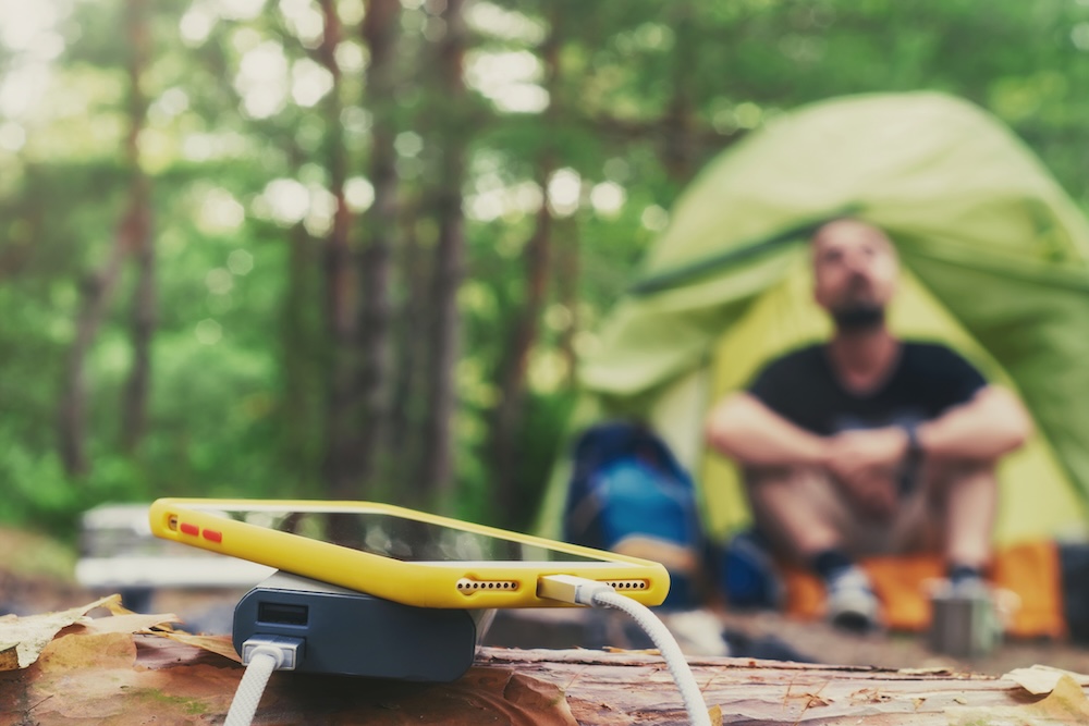 phone charging off a power bank in front of a tent
