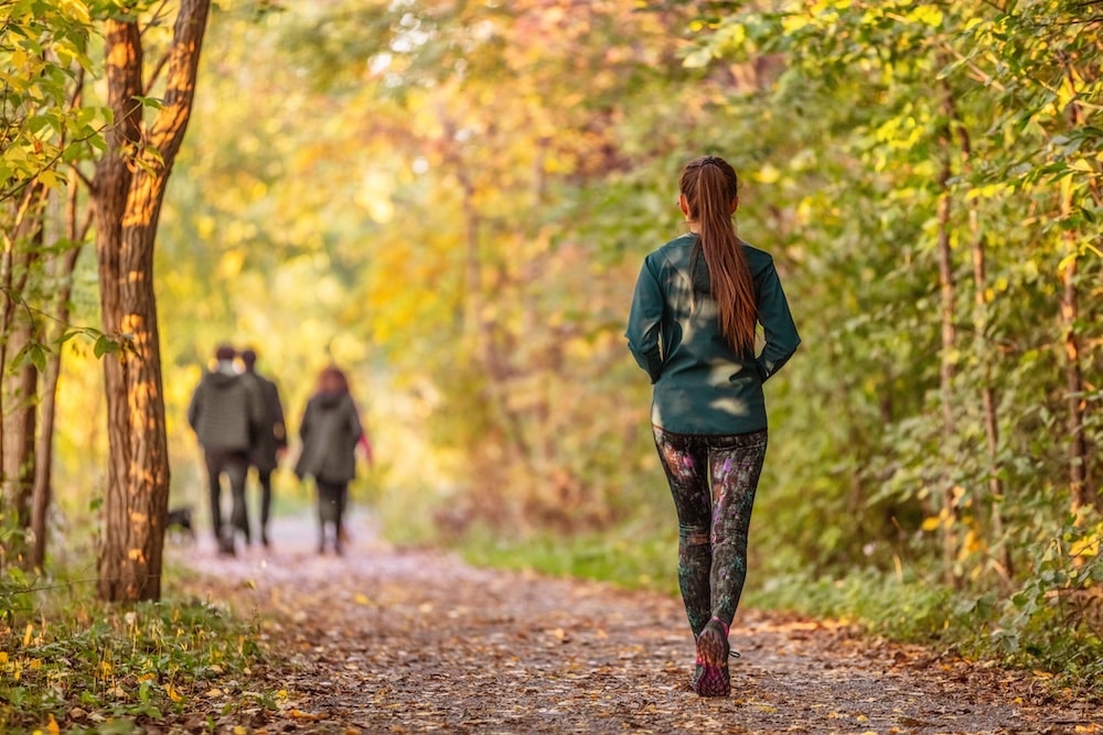 A woman walks through a leafy park