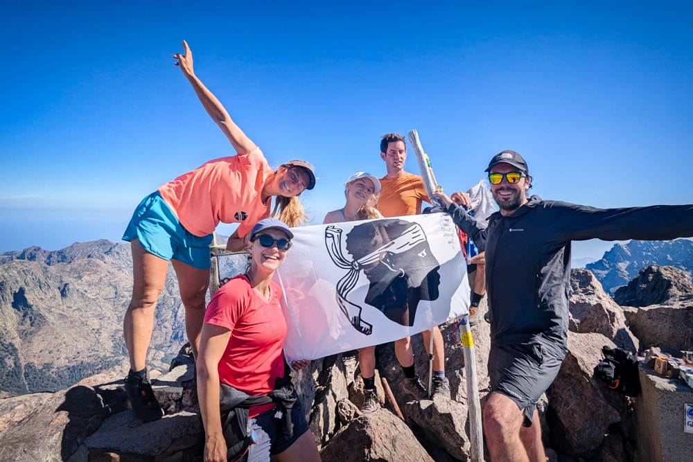 Is the GR20 the toughest trek in Europe? Hikers holding up a Corsican flag on the summit