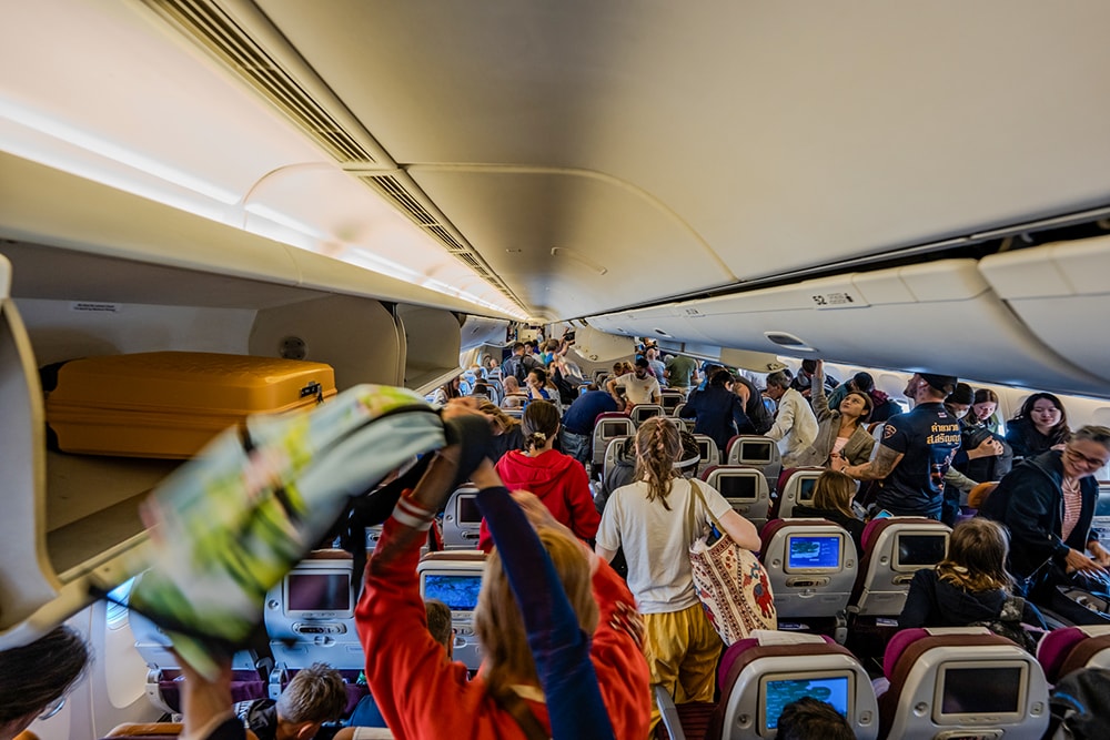 Passengers grab overhead luggage on a flight